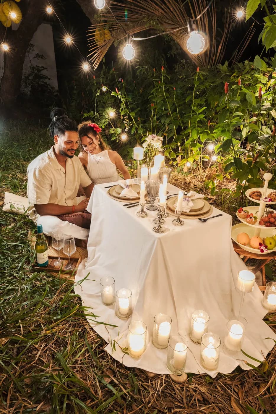 A candlelit table set outside among the trees
