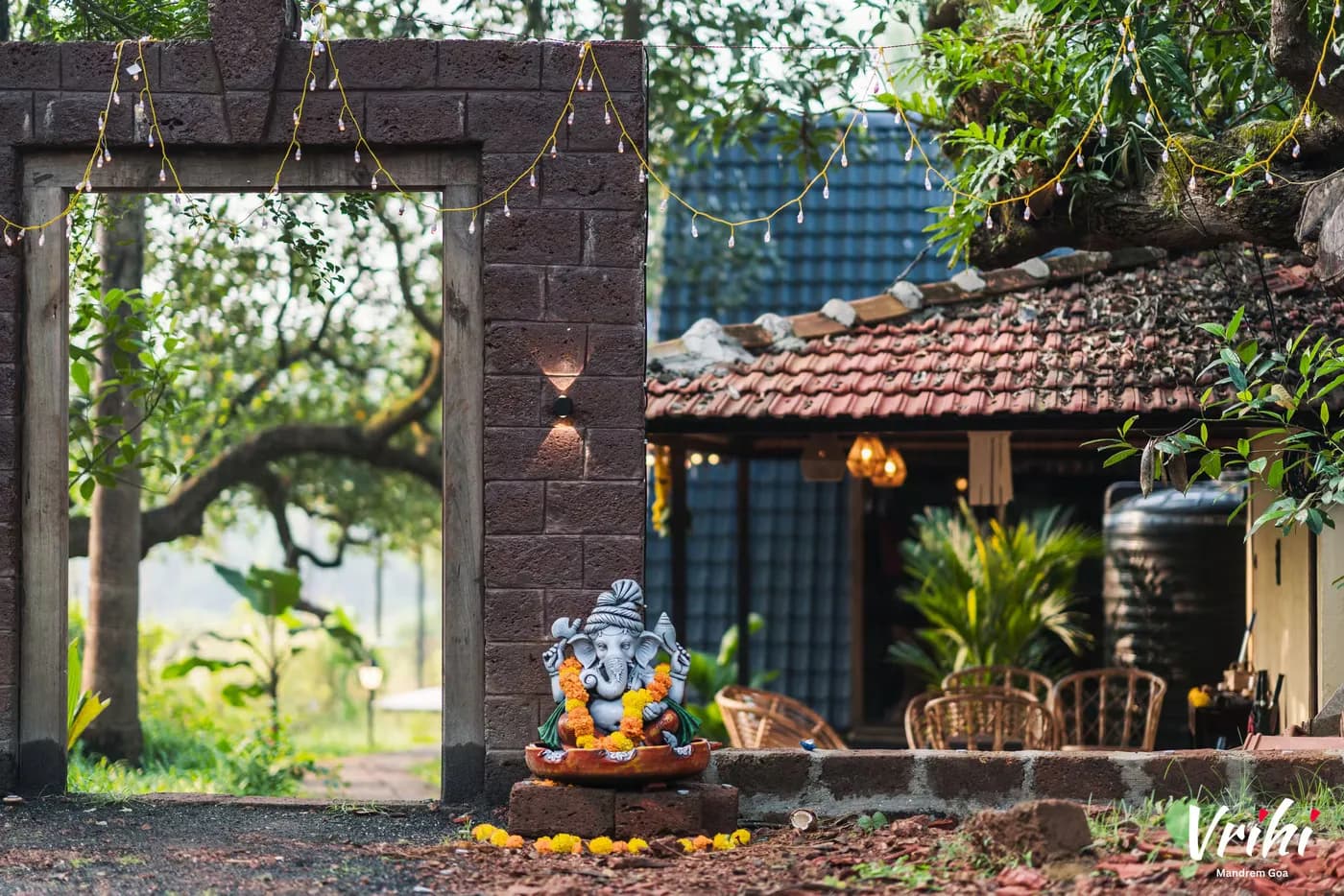 The laterite gate, marigolds and a garlanded Ganesha